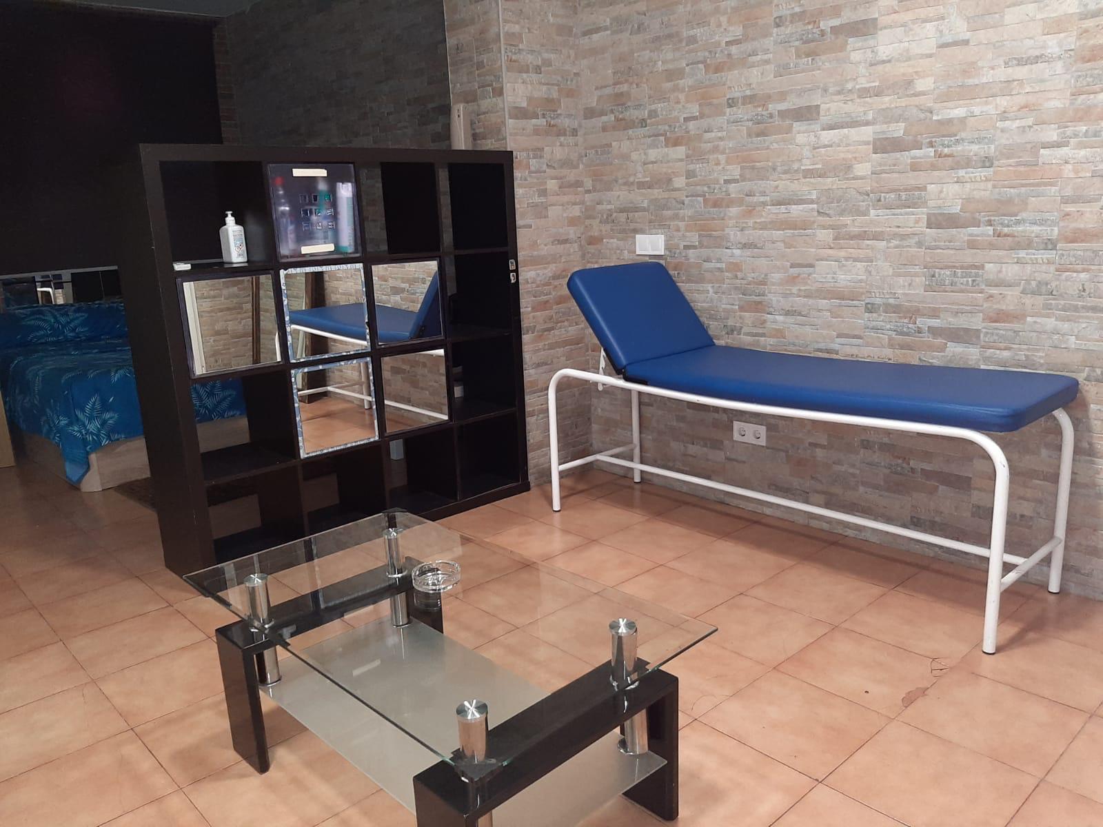 Portazgo Rooms Madrid habitacion con mesa de cristal y camilla de masajes